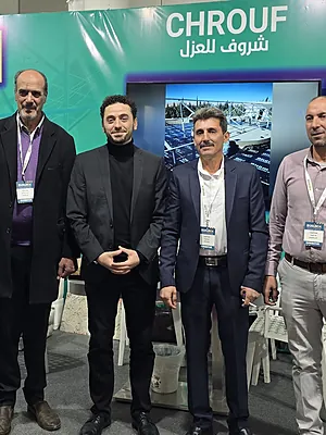 Four men standing in front of a green booth with the word CHROUF in English and Arabic overhead.