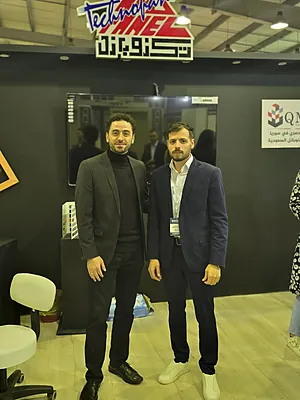 Two men in suits standing indoors at a technology-themed event booth.